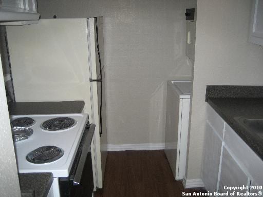 kitchen with white cabinets, white range with electric stovetop, and dark hardwood / wood-style flooring