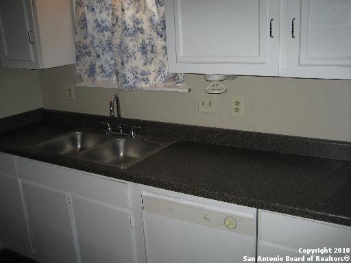 kitchen with dishwasher, white cabinetry, and sink