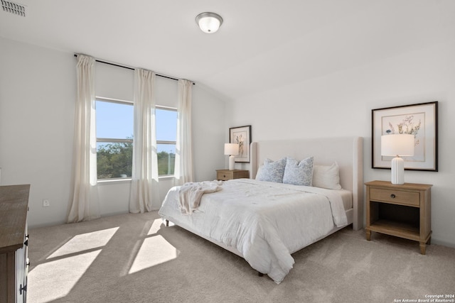 bedroom featuring light colored carpet and lofted ceiling