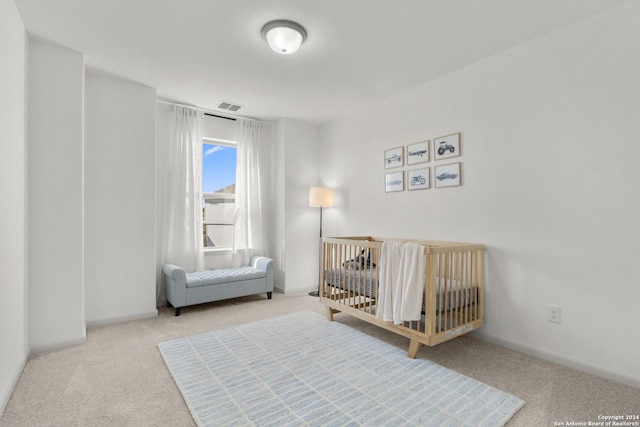 bedroom featuring light carpet and a nursery area