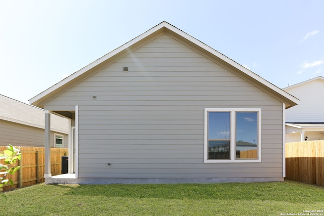 rear view of house with fence and a lawn