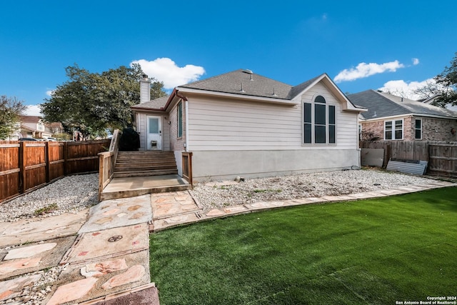 rear view of property featuring a lawn