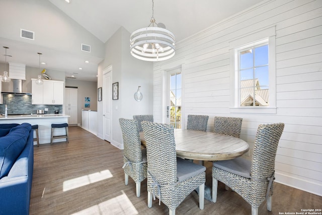 dining room featuring hardwood / wood-style flooring, high vaulted ceiling, and an inviting chandelier