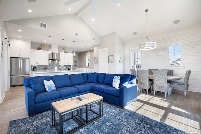 living room featuring wood walls, high vaulted ceiling, ceiling fan with notable chandelier, beam ceiling, and wood-type flooring