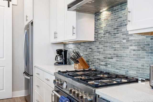 kitchen featuring white cabinetry, stainless steel appliances, tasteful backsplash, light stone counters, and custom exhaust hood