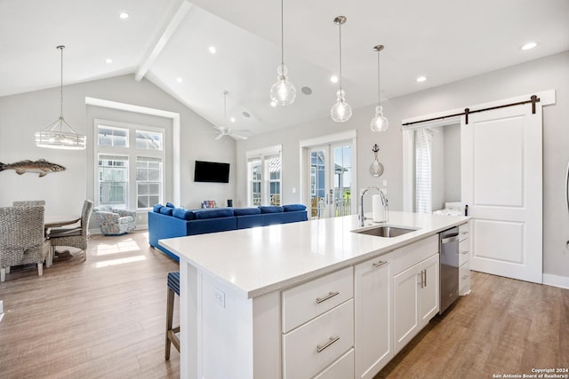 kitchen featuring sink, a barn door, light hardwood / wood-style flooring, a center island with sink, and white cabinets