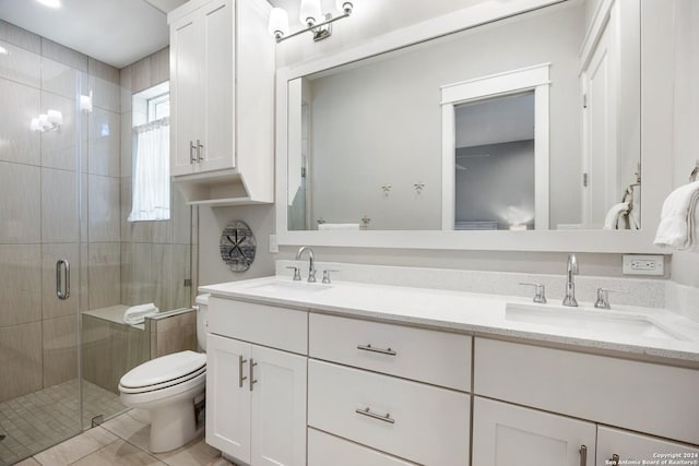 bathroom featuring tile patterned flooring, vanity, toilet, and a shower with shower door