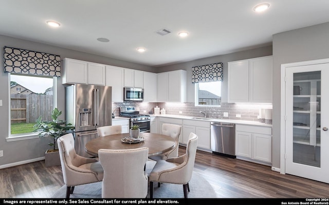 kitchen featuring backsplash, sink, dark hardwood / wood-style floors, white cabinetry, and stainless steel appliances