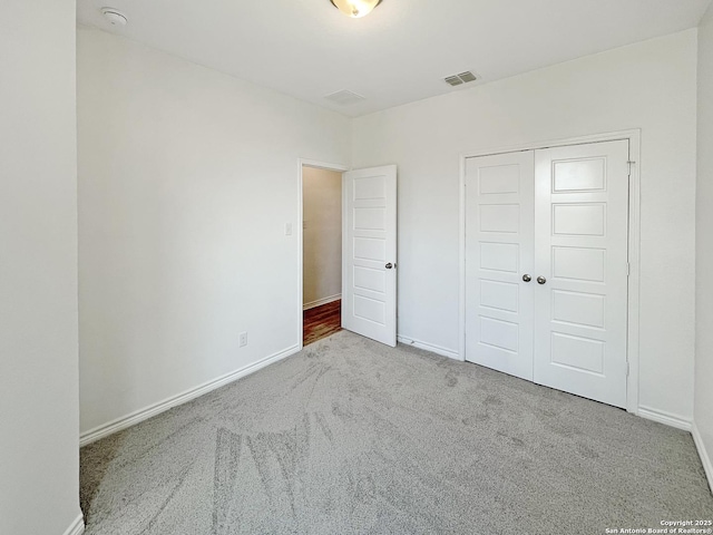 unfurnished bedroom featuring baseboards, visible vents, a closet, and carpet
