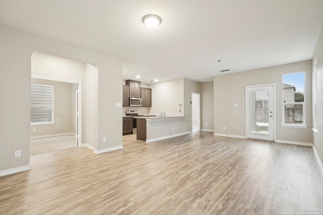 unfurnished living room featuring light hardwood / wood-style flooring and a textured ceiling