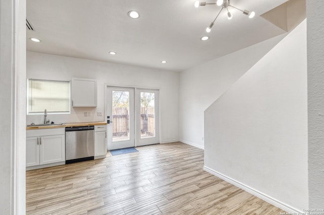 kitchen with dishwasher, wooden counters, white cabinets, and sink