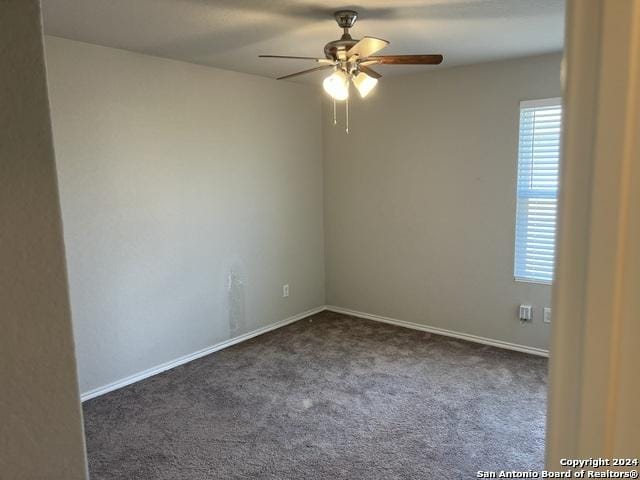 empty room featuring dark carpet and ceiling fan