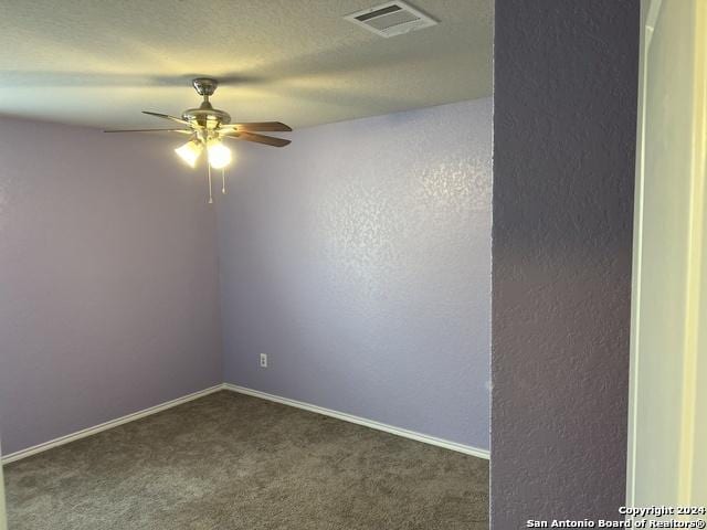 spare room with ceiling fan, dark carpet, and a textured ceiling