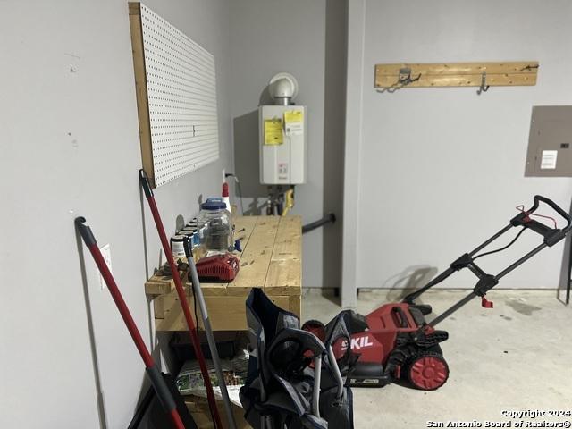 utility room with electric panel and water heater