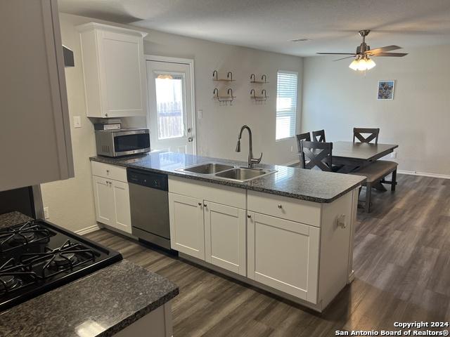 kitchen featuring ceiling fan, sink, dark wood-type flooring, white cabinets, and appliances with stainless steel finishes