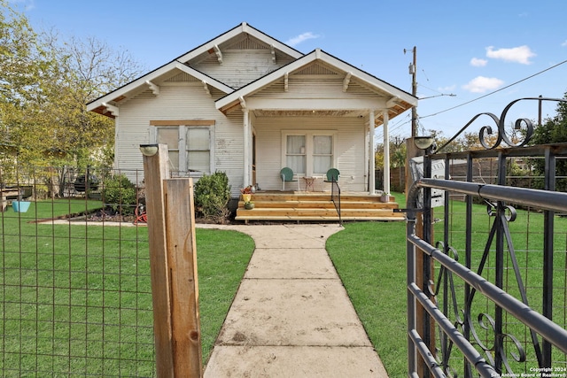 view of front of property with covered porch, fence, and a front lawn