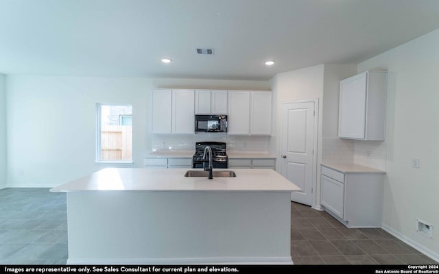 kitchen featuring white cabinets, a center island with sink, and black appliances