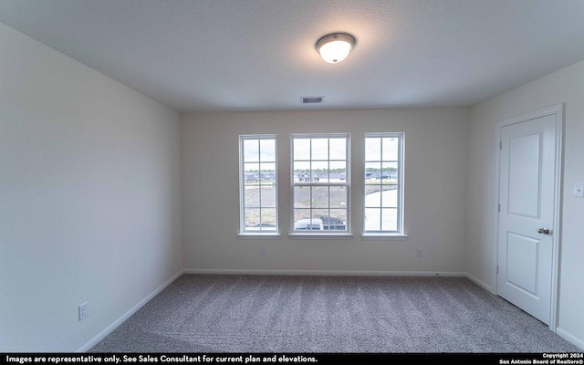 carpeted spare room featuring a textured ceiling