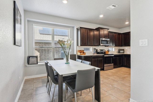 kitchen with decorative backsplash, dark brown cabinets, light tile patterned floors, and appliances with stainless steel finishes