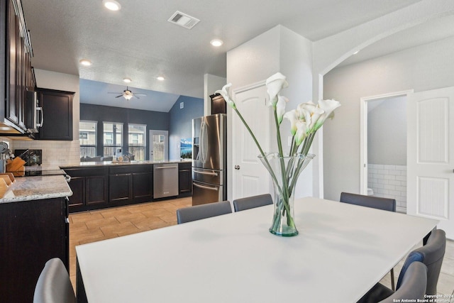 dining space featuring a textured ceiling, vaulted ceiling, ceiling fan, and sink