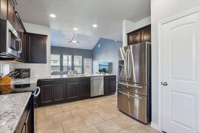 kitchen featuring appliances with stainless steel finishes, tasteful backsplash, light stone counters, vaulted ceiling, and sink