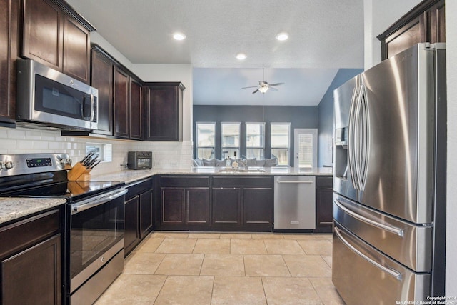 kitchen with ceiling fan, backsplash, dark brown cabinets, light tile patterned floors, and appliances with stainless steel finishes