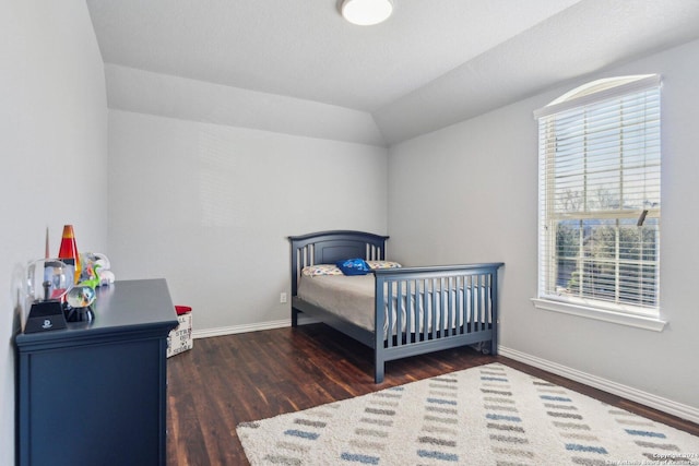 bedroom with a nursery area, dark wood-type flooring, multiple windows, and lofted ceiling