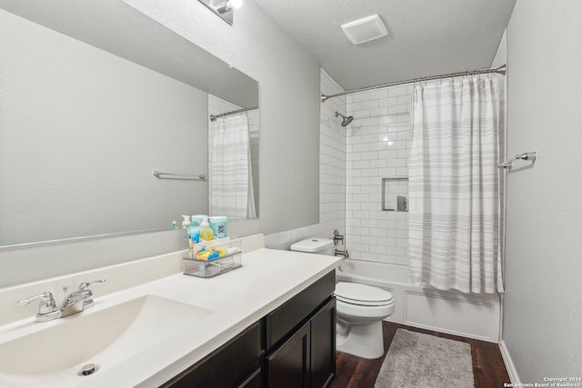 full bathroom with vanity, hardwood / wood-style flooring, toilet, shower / bath combo with shower curtain, and a textured ceiling