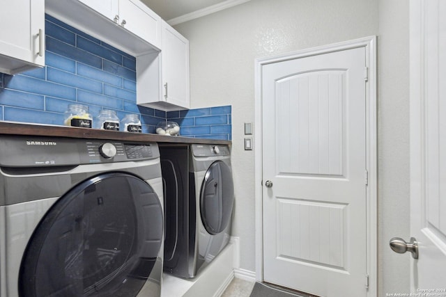 clothes washing area featuring washer and clothes dryer, cabinets, and ornamental molding