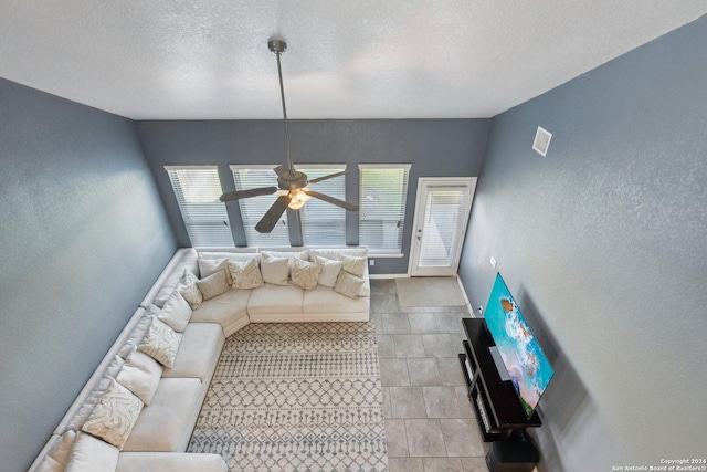 living room featuring ceiling fan and a textured ceiling