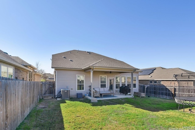 back of property featuring a patio, central air condition unit, ceiling fan, a yard, and a trampoline