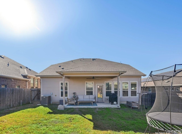 back of house featuring a lawn, a patio area, ceiling fan, and a trampoline