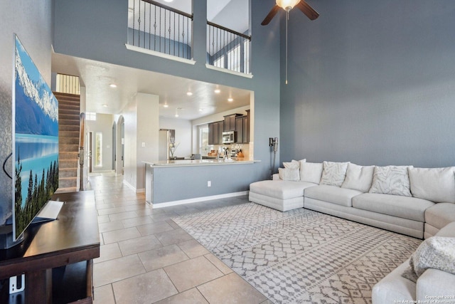 tiled living room with ceiling fan and a high ceiling