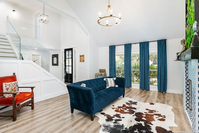 living room with light hardwood / wood-style floors, high vaulted ceiling, and a notable chandelier