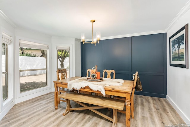 dining space with light hardwood / wood-style flooring, a notable chandelier, and crown molding