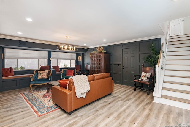 living room featuring light hardwood / wood-style floors, ornamental molding, a wealth of natural light, and an inviting chandelier