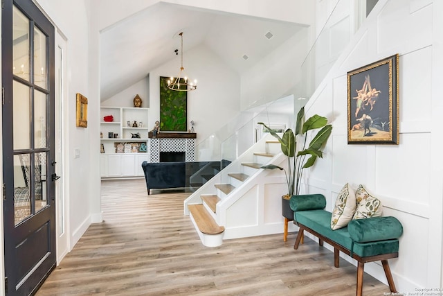 interior space with a fireplace, high vaulted ceiling, a notable chandelier, and light wood-type flooring