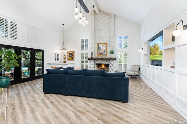 living room with a fireplace, beam ceiling, high vaulted ceiling, and a healthy amount of sunlight