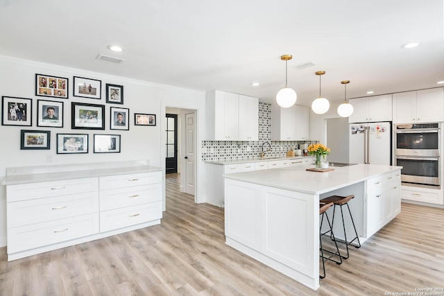 kitchen with pendant lighting, stainless steel double oven, white refrigerator, and white cabinetry