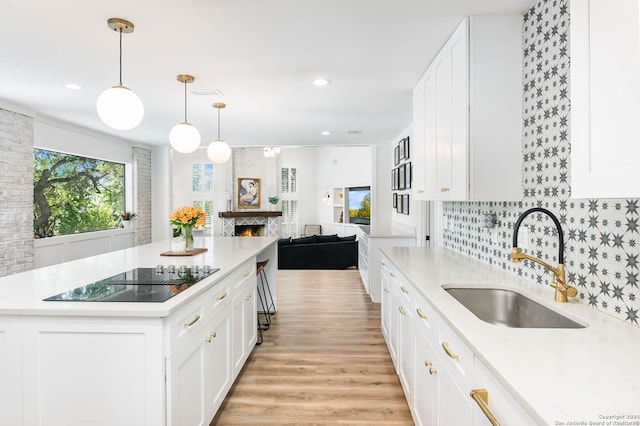 kitchen with white cabinetry, sink, a center island, and decorative light fixtures