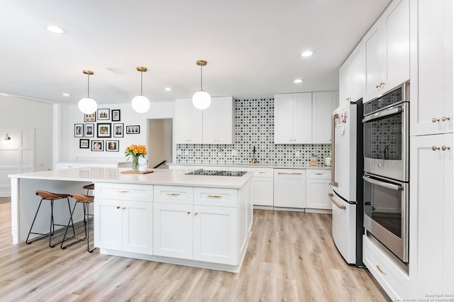 kitchen featuring decorative backsplash, white appliances, pendant lighting, white cabinets, and a center island