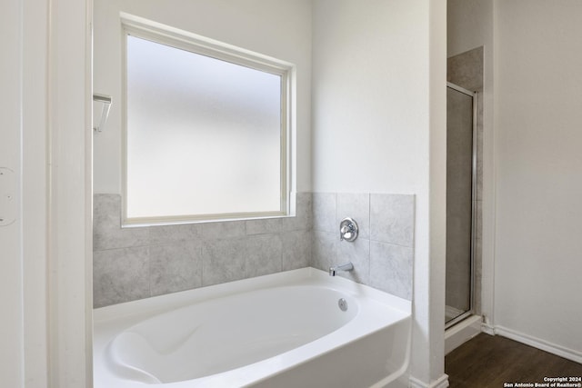 bathroom with wood-type flooring and shower with separate bathtub