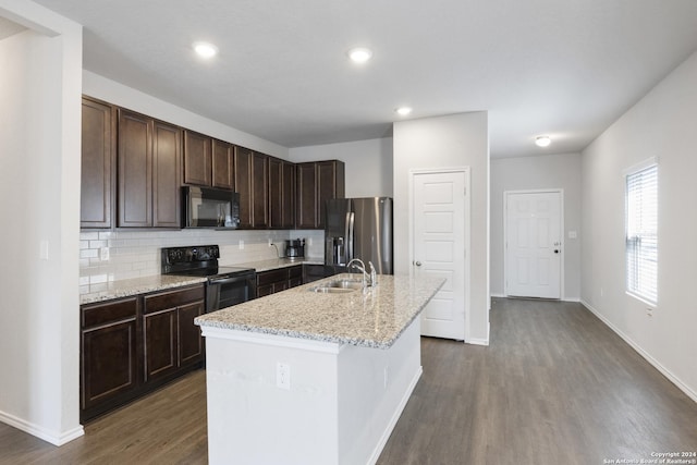 kitchen featuring light stone countertops, sink, a kitchen island with sink, decorative backsplash, and black appliances