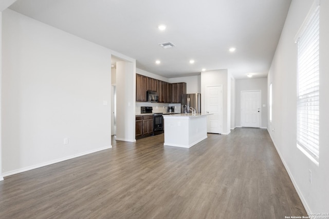 kitchen featuring dark brown cabinetry, hardwood / wood-style floors, an island with sink, and black appliances