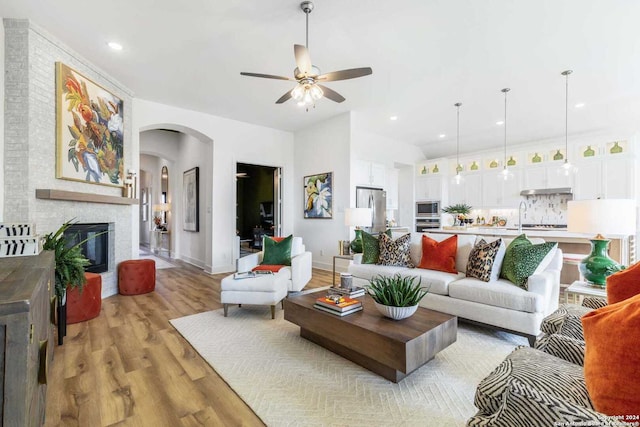 living room with light hardwood / wood-style floors, a brick fireplace, ceiling fan, and sink