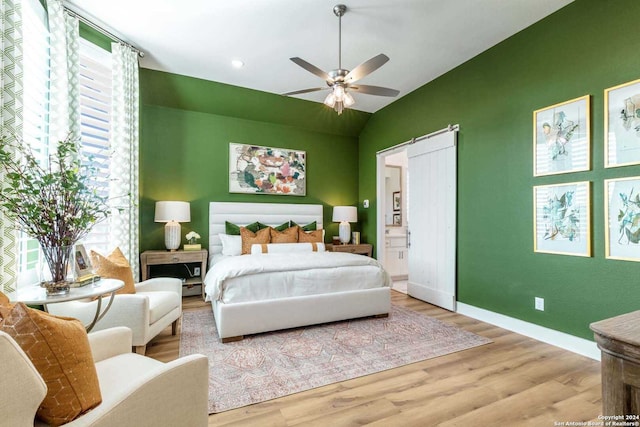 bedroom featuring ensuite bath, light hardwood / wood-style flooring, ceiling fan, and lofted ceiling