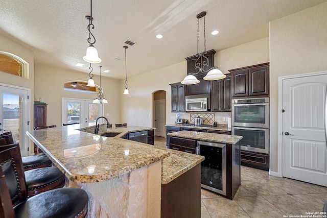 kitchen featuring appliances with stainless steel finishes, a spacious island, hanging light fixtures, and beverage cooler