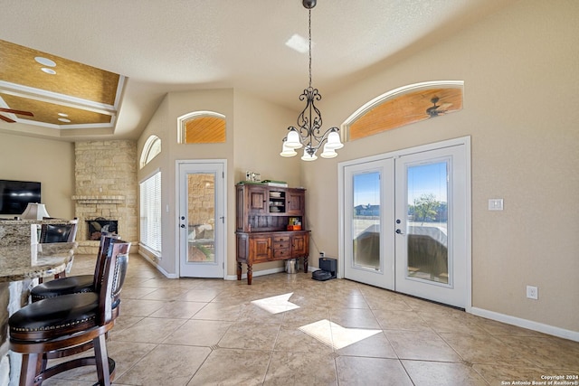 foyer with a fireplace, french doors, high vaulted ceiling, and light tile patterned flooring