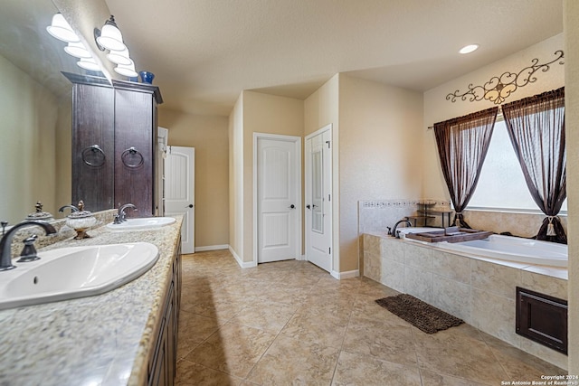 bathroom with tile patterned floors, tiled tub, and vanity