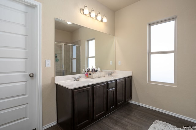 bathroom with hardwood / wood-style floors, vanity, and a shower with door